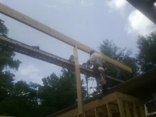 Carpenter setting a ridge beam over a new addition frame — Ice Dam Removal by Roofing Brothers in Freeland